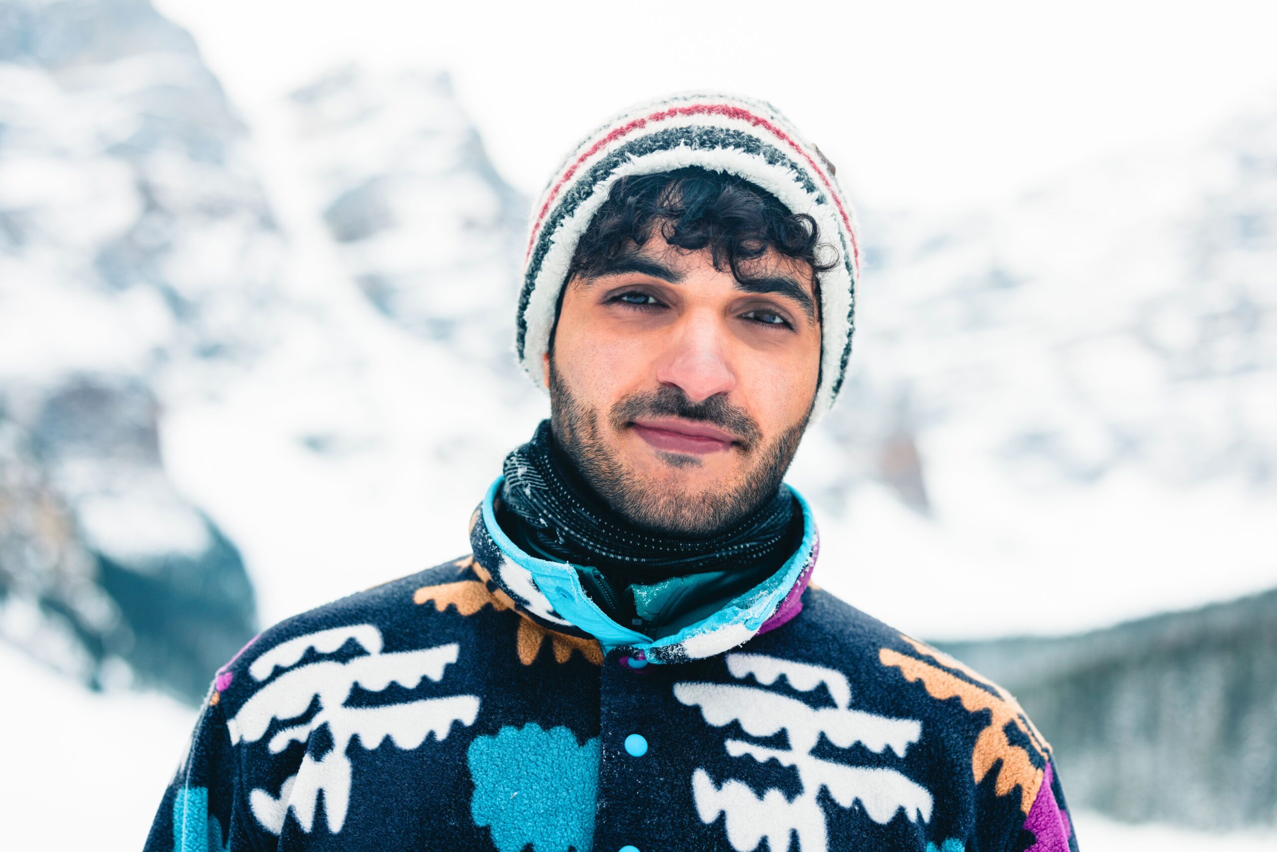 A man in colorful winter attire smiling in snowy Banff National Park.